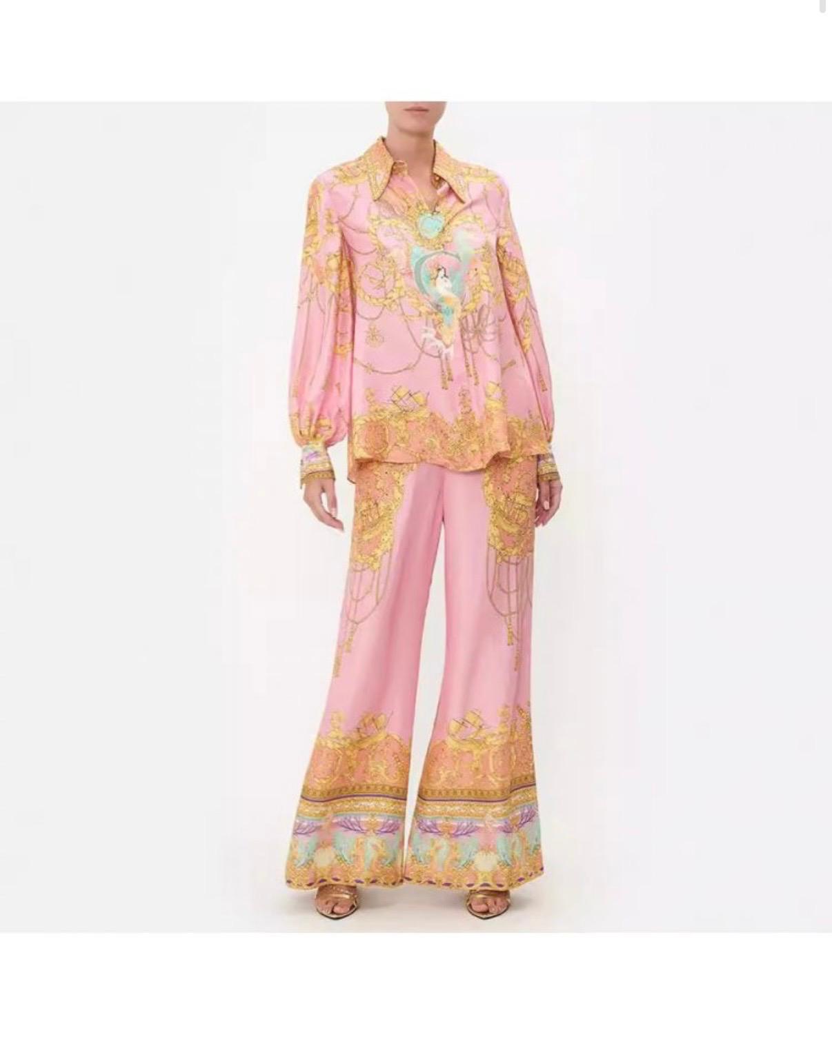 Thia chic pink two-piece set featuring a long-sleeved button-up blouse and wide-leg palazzo pants