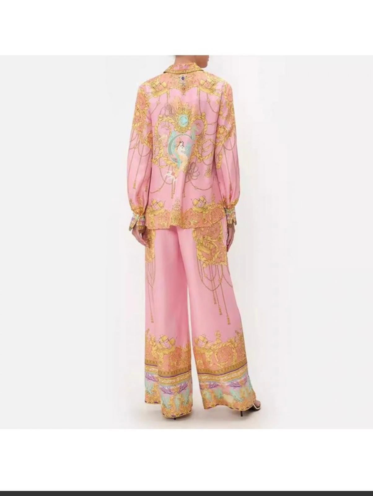 Thia chic pink two-piece set featuring a long-sleeved button-up blouse and wide-leg palazzo pants