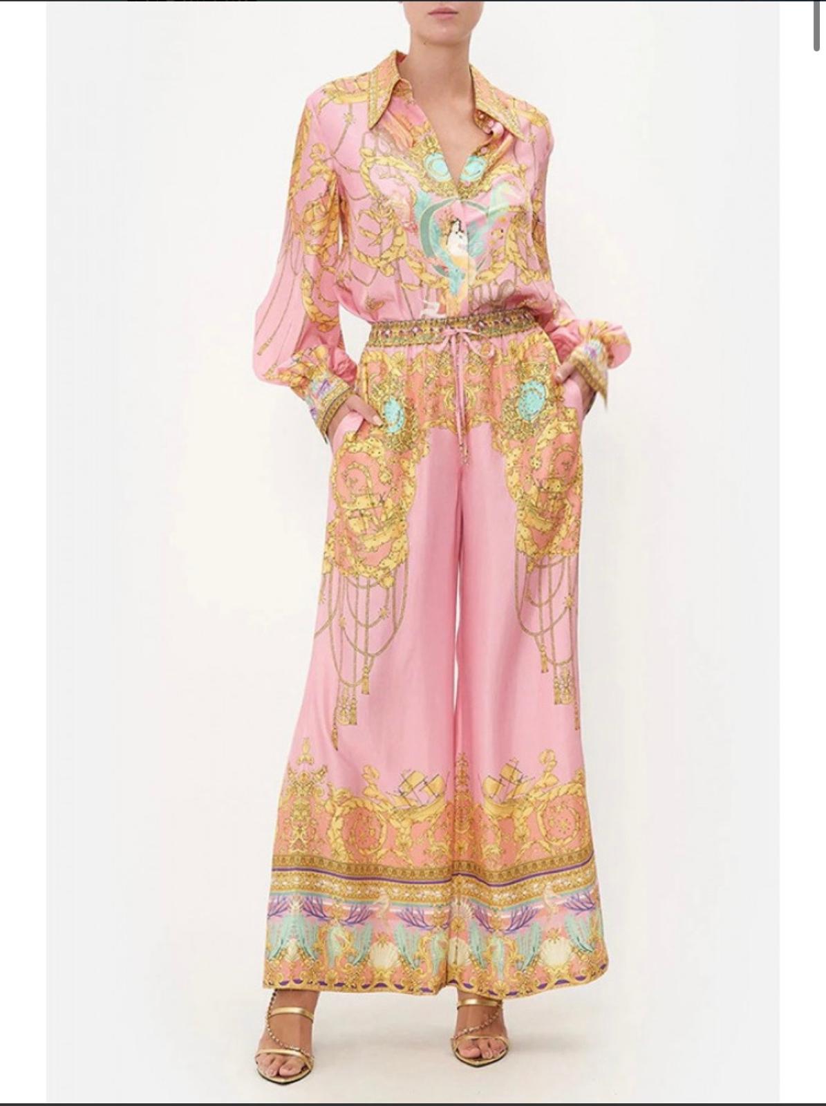 Thia chic pink two-piece set featuring a long-sleeved button-up blouse and wide-leg palazzo pants
